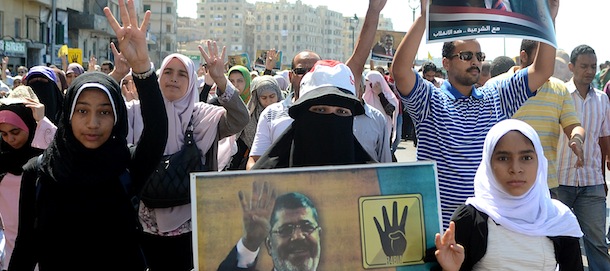Supporters of Egypt's ousted Islamist president Mohamed Morsi hold his portrait and flash a four finger symbol, known as "Rabaa", which means four in Arabic, to remember those killed in the crackdown on the Rabaa al-Adawiya protest camp in Cairo earlier in the year, as they take part in a demonstration against the military on September 20, 2013 along the seafront in the northern coastal city of Alexandria. Egypt's army-backed authorities arrested the spokesman of the Muslim Brotherhood on September 17 and froze the assets of other Islamists, in a new blow to deposed president Mohamed Morsi's supporters. AFP PHOTO / STR (Photo credit should read -/AFP/Getty Images)