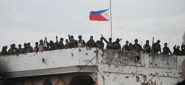 Philippine soldiers stand on the roof of a damaged house as a Philippine flag flutters at half-mast at Martha Street, the scene of some of the heaviest fighting during the stand-off with government forces in Zamboanga, on the southern island of Mindanao on September 28, 2013. A military campaign at a key Philippine port against Muslim gunmen opposed to peace talks ended September 28, with close to 500 rebels killed or captured and nearly 200 hostages freed, the army said. AFP PHOTO (Photo credit should read STR/AFP/Getty Images)