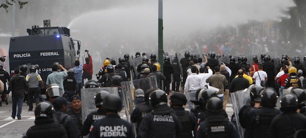 A Federal Police vehicle sprays water on a group of protesters near the Zocalo, Mexico City's main plaza, Friday, Sept. 13, 2013. Minutes after a late-afternoon government deadline for teachers to leave from the city's main plaza, where they have camped out for weeks, riot police moved in, firing tear gas and ducking hurled rocks in a confrontation culminating weeks of protests against an education reform. (AP Photo/Marco Ugarte)