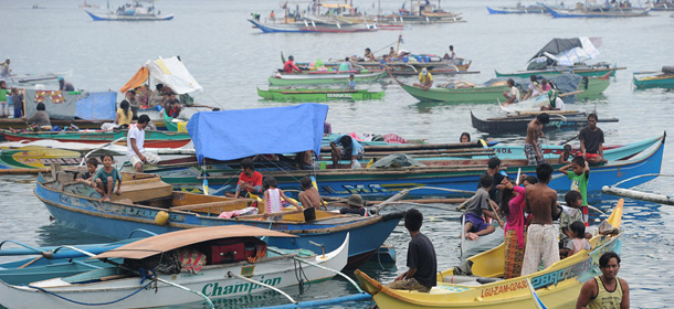 Residents living near the area of a stand-off between the Philippine military and Muslim gunmen in Zamboanga are pictured in boats after evacuating the city's boulevards to the coast on the southern Philippine island of Mindanao on September 11, 2013. Muslim militants were using 180 residents as "human shields" on September 10, Philippine officials said, as they traded gunfire with troops amid burning houses during a standoff after a deadly attack on a southern city. AFP PHOTO / TED ALJIBE (Photo credit should read TED ALJIBE/AFP/Getty Images)