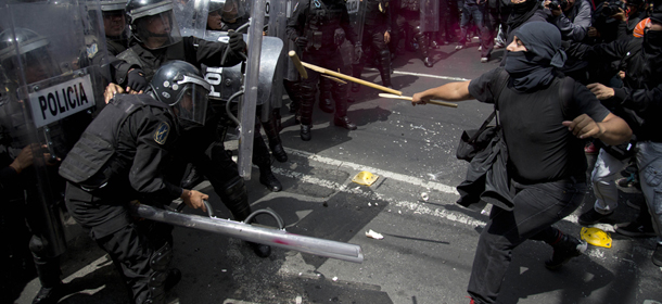 Masked protesters clash with riot police during a march in Mexico City, Sunday, Sept. 1, 2013. Teachers, anarchists and and other groups protesting against the proposed energy and education reforms are marching separately towards the national congress as Mexican president Enrique Pena Nieto sends his Interior Minister to congress to deliver the written version of his first State of the Nation and a day later, Pena Nieto will offer his State of the Nation address. (AP Photo/Eduardo Verdugo)