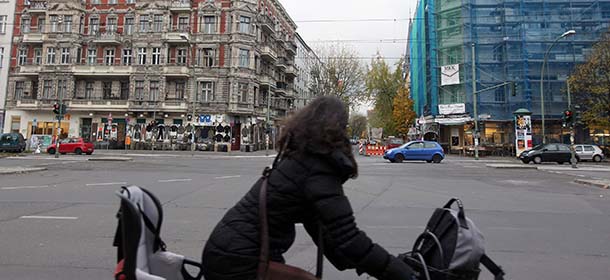 BERLIN, GERMANY - NOVEMBER 09: A woman rides a bicycle past two pre-war buildings, one of which is covered in scaffolding for renovations, in the neighborhood of Prenzlauer Berg on November 9, 2012 in Berlin, Germany. Real estate prices in Berlin have risen by 32 percent since 2007, a much higher rate than the rest of the country. (Photo by Adam Berry/Getty Images)