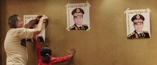 Ahmad Mohammed, a supporter of Defense Minister Gen. Abdel-Fattah el-Sissi, tapes a poster of El-Sissi as Mohammed's niece, Minnah Mostafa Mohammed, 7, helps him before the initiation of a campaign to nominate the minister to run for Egypt's president, at a hotel in Cairo, Egypt, Monday, Sept. 16, 2013. A group of Egyptian professionals, lawyers and ex-army officers have launched a campaign to collect signatures urging the country's military chief to run for president, just two months after he ousted the first elected leader. (AP Photo/Hiro Komae)