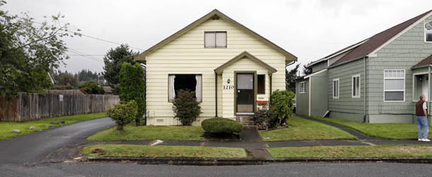This Monday, Sept. 23, 2013 photo shows the childhood home of Kurt Cobain, the late frontman of Nirvana, left, along an alley in Aberdeen, Wash. Cobain's mother is putting the tired, 1.5-story Aberdeen bungalow on the market this week, the same month as the 20th anniversary of Nirvana's final studio album. The home, last assessed at less than $67,000, is being listed for $500,000, but the family would also be happy entering into a partnership with anyone who wants to turn it into a museum. (AP Photo/Elaine Thompson)