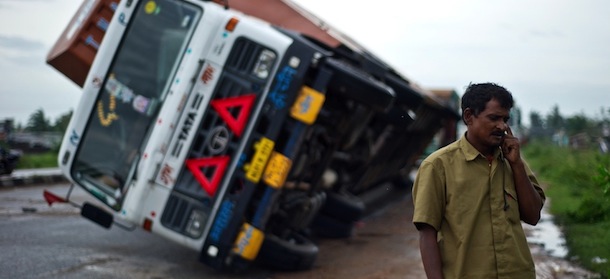 Indian truck driver Jairam Yadav speaks on his mobile phone after his truck carrying Toyota cars was overturned by strong wind on the National Highway linking Andhra Pradesh and Odisha on October 13, 2013. Cyclone Phailin left a trail of destruction along India's east coast and up to seven people dead after the biggest evacuation in the country's history helped minimise casualties. AFP PHOTO/ MANAN VATSYAYANA (Photo credit should read MANAN VATSYAYANA/AFP/Getty Images)