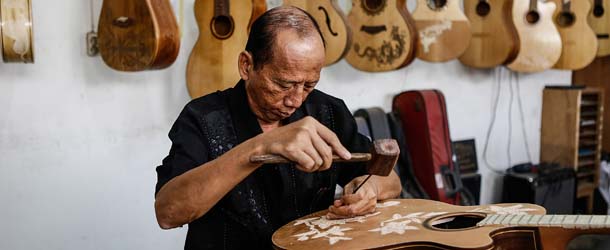 SUKAWATI, BALI - OCTOBER 11: 61 years old Wayan Tuges carves a guitar at his workshop on October 11, 2013 in Kuta, Indonesia. Master woodcarver, Wayan Tuges, began hand-crafting guitars in his small, central-Bali workshop after meeting Montreal business man, Danny Fonfeder in Bali in 2008. Together with American luthier, George Morris the three combined talents to launch Blueberry guitars providing on-of-a-kind instruments that feature unique, hand-carved intricate wood details to customers around the globe. (Photo by Putu Sayoga/Getty Images)