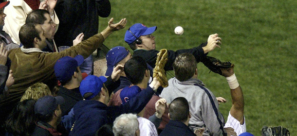 ** FILE ** In this Oct. 14, 2003 file photo, Chicago Cubs left fielder Moises Alou's arm is seen reaching into the stands, at right, unsuccessfully for a foul ball along with a fan identified as Steve Bartman, left, wearing headphones, glasses and Cubs hat, during the eighth inning against the Florida Marlins in Game 6 of the National League Championship Seriesin Chicago. (AP Photo/Morry Gash, File)