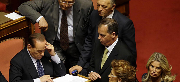 People of Freedom party leader Silvio Berlusconi, left, is surrounded by senators as he checks a document at the Senate, in Rome, Wednesday, Oct. 2, 2013. Italian premier Enrico Letta was putting his government's survival to confidence votes in Parliament on Wednesday amid a divisive split in Silvio Berlusconi's party that could at least temporarily save his fragile ruling coalition. (AP Photo/Gregorio Borgia)