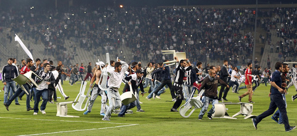 Besiktas fans throw plastic chairs onto the pitch during the Turkish Super League derby soccer match between Besiktas and Galatasaray at Ataturk Olympic Stadium in Istanbul late September 22, 2013. Hundreds of fans halted the Istanbul derby after storming the pitch at Istanbul's Olympic Stadium on Sunday, local media reported. Galatasaray were leading 2-1 in the third minute of added time when the match was halted, sending the players sprinting for the safety of the locker rooms. Picture taken September 22, 2013. REUTERS/Stringer (TURKEY - Tags: SPORT SOCCER CIVIL UNREST TPX IMAGES OF THE DAY)