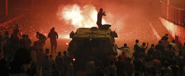 A riot police officer, on a armoured personnel carrier surrounded by anti-Mursi protesters (foreground), fires rubber bullets at members of the Muslim Brotherhood and supporters of ousted Egyptian President Mohamed Mursi along a road at Ramsis square, which leads to Tahrir Square, during clashes at a celebration marking Egypt's 1973 war with Israel, in Cairo October 6, 2013. At least 28 people were killed and more than 90 wounded in clashes during protests in Egypt on Sunday, security sources and state media said, as the crisis since the army seized power three months ago showed no sign of abating. REUTERS/Amr Abdallah Dalsh (EGYPT - Tags: POLITICS CIVIL UNREST TPX IMAGES OF THE DAY)