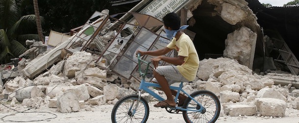 A boy rides a bicycle past a destroyed building in Loon, Bohol a day after an earthquake hit central Philippines October 16, 2013. REUTERS/Erik De Castro (PHILIPPINES &#8211; Tags: DISASTER ENVIRONMENT SOCIETY)
