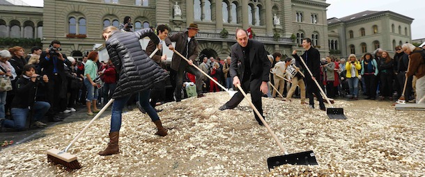 Committee members use brooms and shovels to spread out five cent coins over the Federal Square during an event organised by the Committee for the initiative "CHF 2,500 monthly for everyone" (Grundeinkommen) in Bern October 4, 2013. The Committee delivered 126,000 signatures to the Chancellery on Friday to propose a change in the constitution to implement their initiative. The initiative aims to have a minimum monthly disposal household income of CHF 2,500 (US$ 2,700) given by the government to every citizen living in Switzerland. REUTERS/Denis Balibouse (SWITZERLAND - Tags: POLITICS CIVIL UNREST)