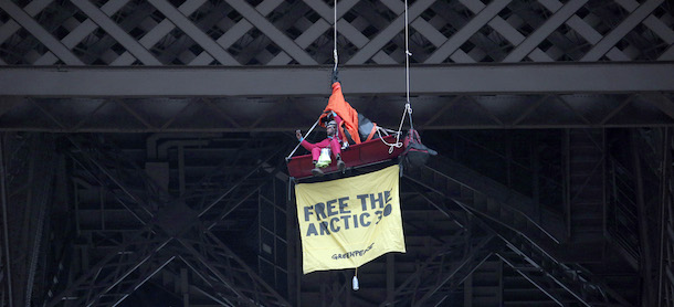 A Greenpeace activist, with a banner reading &#8220;Free the Arctic 30&#8243;, takes a photograph as he protests suspended from the second floor of the Eiffel Tower against Russia&#8217;s detention of members of the environmental group, Paris, Saturday, Oct. 26, 2013. Russia&#8217;s main investigative agency said Wednesday, Oct. 23, 2013 that it has dropped piracy charges against jailed Greenpeace activists and charged them instead with hooliganism, which could still mean years in prison. Banner reads: &#8220;Militants in prison, climate in danger&#8221;. (AP Photo/Christophe Ena)
