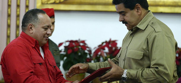 The president of the Venezuelan National Assembly, Diosdado Cabello (L), gives Venezuelan President Nicolas Maduro (R) a document with a copy of a new law of wide-ranging special powers to rule by decree for one year in Caracas on November 19, 2013. Maduro requested the special powers last month, citing the need to fight corruption and take on opponents who are waging "economic warfare" against his government. AFP PHOTO/JUAN BARRETO (Photo credit should read JUAN BARRETO/AFP/Getty Images)