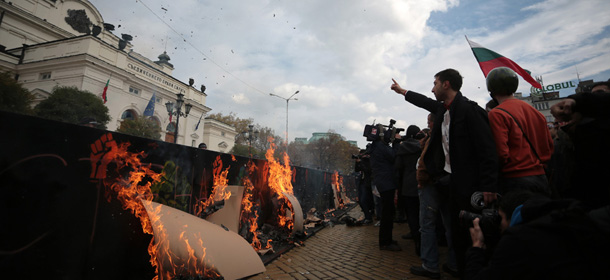 Students chant slogans as they set posters on fire in front of the Bulgarian Parliament during a protest in Sofia, Wednesday, Nov. 20, 2013. Three different rallies were held on Wednesday in front of the parliament building which was cordoned off by riot police. Protesters blocked major intersections in central Sofia, but no clashes or injuries were immediately reported. (AP Photo/Valentina Petrova)