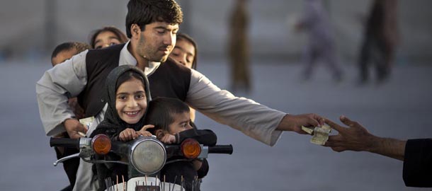 An Afghan man with his five children on his motorbike pays money to enter a park in Kandahar, southern Afghanistan, Friday, Nov 1, 2013. On Fridays, a day of weekly prayers, children and their families traditionally gather in one of the few parks. (AP Photo/Anja Niedringhaus)
