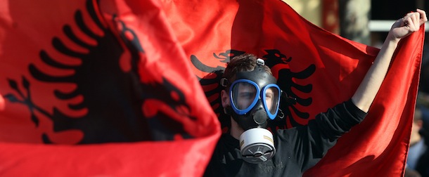 An Albanian environmental activist wears a gas mask and holds up a national flag as he takes part in a protest in front of the Albanian parliament in Tirana on November 14, 2013, over the possibility of the Republic of Albania processing and destroying 1.000 tons of chemical weapons from Syria in its military facilities. Albanian Prime Minister Edi Rama said today that his country has yet to decide whether it will undertake the destruction of Syrian chemical weaponry on its soil as hundreds protested against such a move. Albania, along with France, Belgium, have been mooted as possible sites for the dismantling of Syria's entire chemical arsenal, estimated at about 1,000 tonnes. AFP PHOTO / GENT SHKULLAKU