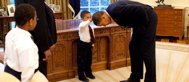 President Barack Obama bends over so the son of a White House staff member can pat his head during a visit to the Oval Office May 8, 2009. Official White House Photo by Pete Souza. This official White House photograph is being made available for publication by news organizations and/or for personal use printing by the subject(s) of the photograph. The photograph may not be manipulated in any way or used in materials, advertisements, products, or promotions that in any way suggest approval or endorsement of the President, the First Family, or the White House.