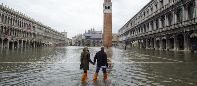 VENICE, ITALY - NOVEMBER 19: A couple walks in a flooded Saint Mark's Square during high waters on November 19, 2013 in Venice, Italy. Venice will be affected by the high water for the next few days due to the passage of Cyclone Cleopatra that hit the Italian island of Sardinia causing devastating flooding, which has left at least 17 dead. (Photo by Marco Secchi/Getty Images)