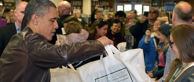 WASHINGTON, DC - NOVEMBER 30: (AFP OUT) U.S. President Barack Obama picks up his purchases from the checkout counter during a shopping trip to the independent bookstore Politics & Prose, November 30, 2013 in Washington, DC. The shopping coincided with Small Business Saturday, a tradition to boost shopping for smaller merchants. (Photo by Mike Theiler-Pool/Getty Images)