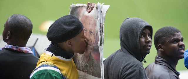 A man kisses the portrait of South African former president Nelson Mandela during his memorial service at the FNB Stadium (Soccer City) in Johannesburg on December 10, 2013. Mandela, the revered icon of the anti-apartheid struggle in South Africa and one of the towering political figures of the 20th century, died in Johannesburg on December 5 at age 95. AFP PHOTO / ODD ANDERSEN (Photo credit should read ODD ANDERSEN/AFP/Getty Images)