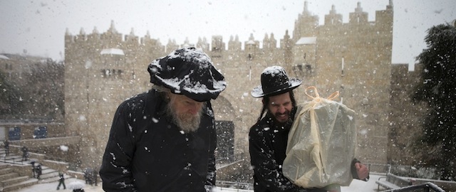 JERUSALEM, ISRAEL - DECEMBER 12: Ultra orthodox jews walk past the Damascus gate on December 12, 2013 outside Jerusalem's old city, Israel. A heavy winter storm hit much of the Middle East yesterday evening into today, forcing the closure of roads and schools while covering widespread areas with snow and ice. (Photo by Uriel Sinai/Getty Images)