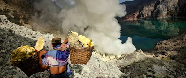 BANYUWANGI, EAST JAVA - DECEMBER 17: A miner carry sulfur during an annual offering ceremony on the Ijen volcano on December 17, 2013 in Yogyakarta, Indonesia. The ritual is performed by the sulfur miners of Mount Ijen who slaughter a goat and then bury the head in the crater of mount Ijen. The sacrifice is performed to ward off potential disasters for the next year. The Ijen crater rises to 2,386m, with a depth of over 175m, making it one of the world's largest craters. Sulphur mining is a major industry in the region, made possible by an active vent at the edge of a lake, but the work is not without risks as the acidity of the water in the crater is high enough to dissolve clothing and cause breathing problems. (Photo by Ulet Ifansasti/Getty Images)
