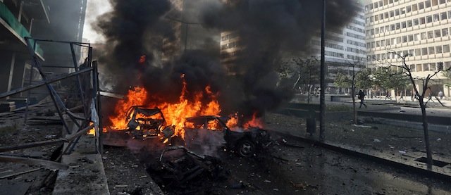 Flames blaze from vehicles at the scene of an explosion in Beirut, Lebanon, Friday, Dec. 27, 2013. A strong explosion has shaken the Lebanese capital, sending black smoke billowing from the center of Beirut. The blast went off a few hundred meters (yards) from the government headquarters and parliament building. (AP Photo/Bilal Hussein)