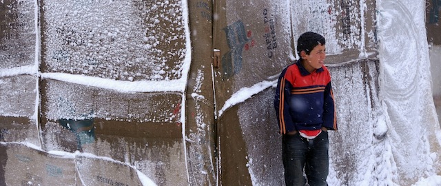 A Syrian refugee boy stands outside his tent as a heavy snowstorm batters the region, in a camp for Syrians who fled their country’s civil war, in the Bekaa valley, eastern Lebanon, Wednesday, Dec. 11, 2013. The United Nations refugee agency says it is "extremely concerned" for hundreds of thousands of Syrian refugees scattered across the region amid a snowstorm with high winds and torrential rains. (AP Photo)