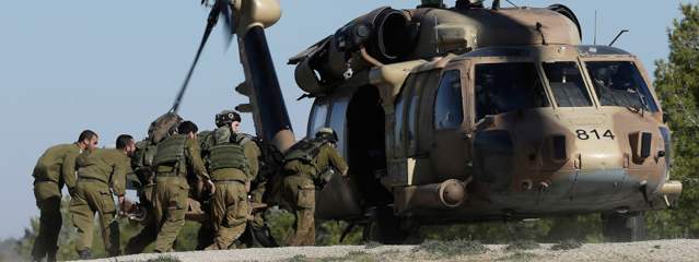 Israeli army soldiers carry a civilian shot near the Israel and Gaza border to a helicopter, Tuesday, Dec. 24, 2013. The man, an Israeli civilian, was shot as he performed maintenance work on the border fence and pronounced dead on arrival to a hospital. Israeli air and ground forces launched a series of attacks Tuesday on targets across the Gaza Strip, killing a young girl and wounding 10 in response to the deadly shooting of an Israeli civilian by a Palestinian sniper. It was the heaviest burst of violence in the volatile area since November 2012, when Israel and Hamas' rulers engaged in eight days of heavy fighting. (AP Photo/Tsafrir Abayov)