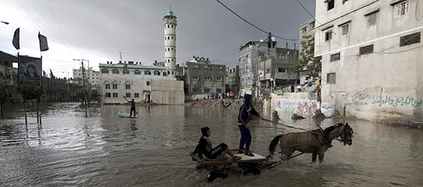 Palestinian youths cross a flooded street on a horse cart following heavy rainfall in Gaza City on December 13, 2013. In the Gaza Strip, which has been in the grip of a fuel crisis that has affected hospitals, sanitation services and sewerage, torrential rains filled the streets with floodwater and overflowing sewage, and forced the closure of schools and banks AFP PHOTO/MOHAMMED ABED (Photo credit should read MOHAMMED ABED/AFP/Getty Images)
