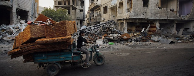 In this photo taken Thursday, Nov. 21, 2013 a Syrian man carries his furniture after his home was destroyed during clashes between the Sunni-dominated Free Syrian Army and Syrian soldiers loyal to Syria's President Bashar Assad, supported by Iraqi and Lebanese Shiite fighters, in the town of Hejeira, which Syrian troops captured, in the countryside of Damascus, Syria. (AP Photo/Jaber al-Helo)