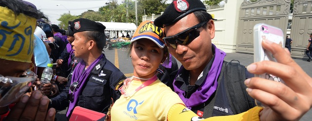 An anti-government protester takes her photograph with a Thai policeman on the road leading to the Metrpolitan police headquarters in Bangkok on December 3, 2013. Hundreds of Thai opposition protesters entered the government headquarters unopposed on December 3, after police said they would offer no resistance to the demonstrators who have vowed to topple Prime Minister Yingluck Shinawatra. AFP PHOTO/Indranil MUKHERJEE (Photo credit should read INDRANIL MUKHERJEE/AFP/Getty Images)