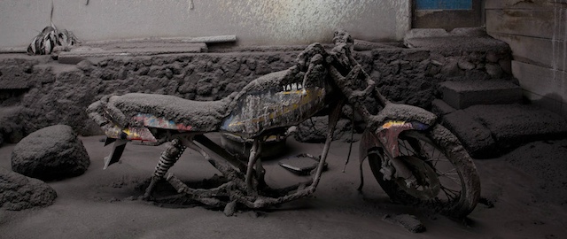 SIGARANG GARANG, NORTH SUMATRA, INDONESIA - JANUARY 12: An covered a motorcycle by ash and mud from eruption of Mount Sinabung following further eruptions of Mount Sinabung on January 12, 2014 in Sigarang Garang village, Karo District, North Sumatra, Indonesia. The number of displaced people has increased to around 25,000 in Western Indonesia as Mount Sinabung continues to spew ash and smoke after a series of several eruptions since September. Eleven deaths have now been recorded as a result of the eruptions with hundreds more falling ill. Officials expect the number of evacuees to rise as volcanic activity remains high. (Photo by Ulet Ifansasti/Getty Images)