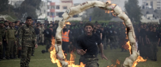A Palestinian student jumps through a burning ring during a graduation ceremony for a military-style training programme in Gaza City on January 14, 2014. Some 13,000 students joined the training, which is aimed at preparing them for "liberating Palestine from Israel", Hamas officials said. AFP PHOTO/MOHAMMED ABED (Photo credit should read MOHAMMED ABED/AFP/Getty Images)