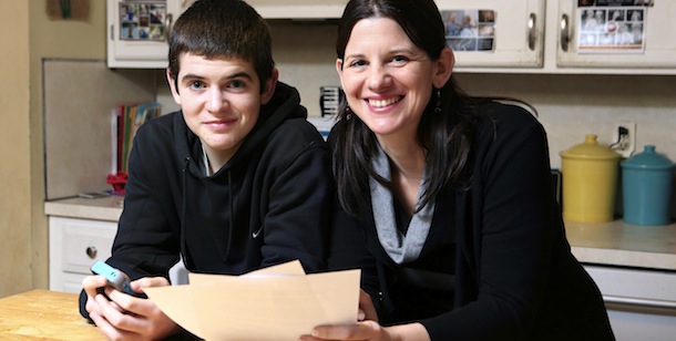 In this Jan. 4, 2013, photo, Janell Burley Hofmann, right, poses with her son Gregory at their home in Sandwich, Mass. Janell holds a copy of the contract she drafted and that Gregory signed as a condition for receiving his first Apple iPhone. (AP Photo/Michael Dwyer)