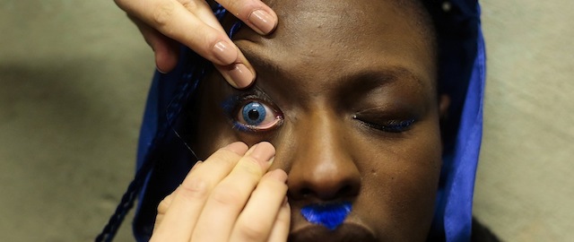 A model gets fitted with a blue contact lens to present a creation from Patrick Mohr's Autumn Winter 2014 collection during the Mercedes Benz Fashion Week in Berlin, Tuesday, Jan. 14, 2014. (AP Photo/Markus Schreiber)