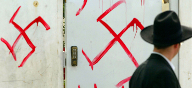 PETAH TIKVA, ISRAEL - MARCH 5: (ISRAEL OUT) A Jewish man looks at anti-semitic graffiti which was sprayed on the gate of a synagogue March 5, 2006 in Petah Tikva, near Tel Aviv, in central Israel. Police are investigating the incident after inscriptions, in Hebrew, "death to Jews" and swastika drawings were found with the signature "white power." (Photo by Uriel Sinai/Getty Images)