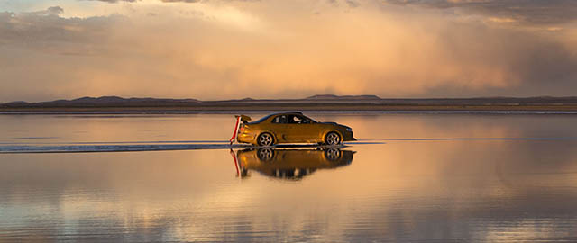 The sky is reflected on the Uyuni Salt Flats as a car drives by in Uyuni, Bolivia, Saturday, Jan. 11, 2014. The motorcycles and quads of the Dakar Rally will race through parts of the Uyuni Salt Flats on Jan. 13, 2014. (AP Photo/Victor R. Caivano)