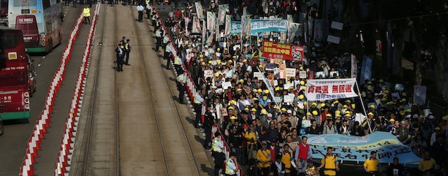 Thousands of protesters march during a demonstration at new year day in Hong Kong Wednesday, Jan. 1, 2014 as the protesters demanded universal suffrage for the people of Hong Kong. The white banner, right, reads "Real universal suffrage, No filtering." (AP Photo/Kin Cheung)