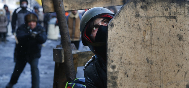 Protesters shield, during clashes with police, in central Kiev, Ukraine, Thursday Jan. 23, 2014. Thick black smoke from burning tires engulfed parts of downtown Kiev as an ultimatum issued by the opposition to the president to call early election or face street rage was set to expire with no sign of a compromise on Thursday. (AP Photo/Sergei Grits)