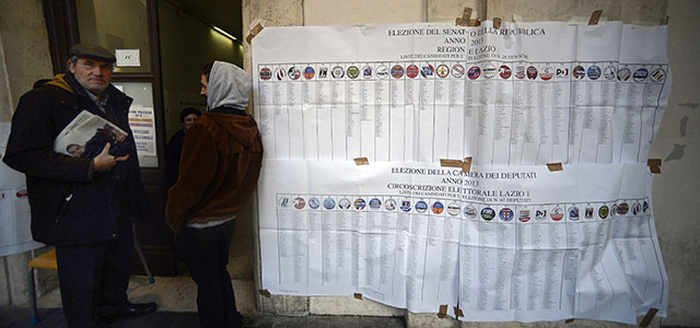 Men stand by electoral banners before voting at a polling station in downtown Rome on February 24,2013, as part of Italy's general elections. The centre-left is the favourite of this vote, as Europe held its breath for signs of fresh instability in the eurozone's third economy.AFP PHOTO / FILIPPO MONTEFORTE (Photo credit should read FILIPPO MONTEFORTE/AFP/Getty Images)