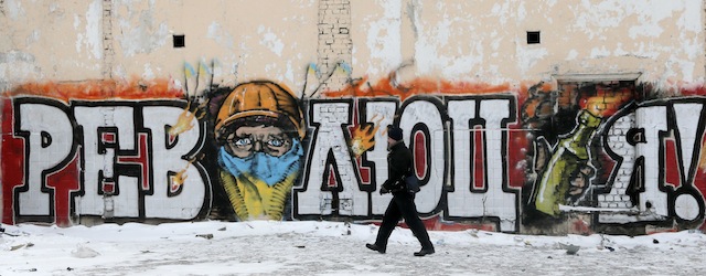 A man passes by some graffiti in the center of Kiev, Ukraine, Wednesday, Jan. 29, 2014. Writing on the wall reads 'Revolution'. Ukraine's parliament is considering measures to grant amnesty to those arrested during weeks of protests in the crisis-torn country, but possibly with conditions attached that would be unacceptable to the opposition. (AP Photo/Efrem Lukatsky)