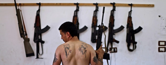 FILE - In this Sunday, Aug. 26, 2012 file photo, Syrian rebel fighter Tawfiq Hassan, 23, a former butcher, poses for a picture, after returning from fighting against Syrian army forces in Aleppo, at a rebel headquarters in Marea on the outskirts of Aleppo city, Syria. Syria’s uprising was not destined to be quick. Instead, the largely peaceful protest movement that spread across the nation slowly turned into an armed insurgency and eventually a full-blown civil war. More than 130,000 people have been killed, and more than 2 million more have fled the country. Nearly three years after the crisis began, Syria's government and opposition are set to meet in Geneva this week for the first direct talks aimed at ending the conflict. (AP Photo/Muhammed Muheisen, File)