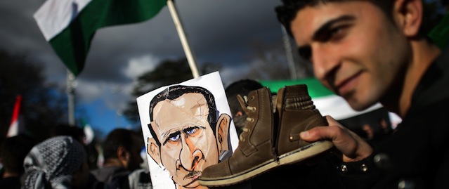 Demonstrators trample sketches depicting Syrian President Bashar al-Assad during a protest against his regime outside the United Nations offices in Geneva on January 24, 2014. Syria's regime threatened to quit peace talks in Geneva as UN-backed efforts to bring the country's warring sides together stumbled on their first day. AFP PHOTO / FABRICE COFFRINI (Photo credit should read FABRICE COFFRINI/AFP/Getty Images)