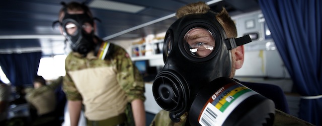 Member of Danish military personnel wearing a protective masks carry out emergency drills aboard the Danish frigate, on the sea between Cyprus and Syria, Friday, Jan. 3, 2014. Two cargo ships and their warship escorts will set Friday from the Cypriot port of Limassol to waters near Syria where they will wait for orders on when they can head to the Syrian port of Latakia to pick up more than 1,000 tons of chemical agents. (AP Photo/Petros Karadjias)