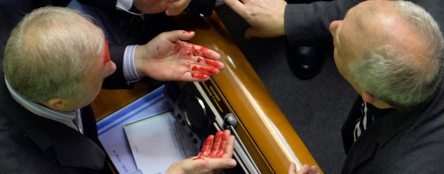 A deputy of the pro-Russian majority (L) bleeds following an argument with a pro-EU opposition MP during a parliament session to debate the 2014 state budget in Kiev on January 14, 2014. The Ukrainian government approved a programme of cooperation with former Soviet states that have joined the Customs Union, although rapprochement with the Russia-led bloc has fuelled continuing pro-Europe protests in Kiev. AFP PHOTO/ SERGEI SUPINSKY (Photo credit should read SERGEI SUPINSKY/AFP/Getty Images)