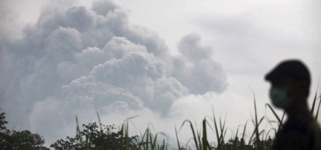 RETRANSMISSION WITH CORRECT CREATION DATE - A man watches from Mbaladak village in Blitar, East Java, Indonesia, as Mount Kelud erupts Friday, Feb. 14, 2014. Volcanic ash from a major eruption in Indonesia shrouded a large swath of the country's most densely populated island on Friday, closed three international airports and sent thousands fleeing. (AP Photo/Trisnadi)