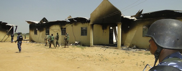 In this photo taken on Monday, Oct. 28, 2013, police and soldiers stand in front of a burnt out army barracks following an attack by Boko Haram in in Damaturu, Nigeria. Nigerian military and hospital reports indicate a 5-hour-long battle between Islamic extremists and troops in the capital of Nigeria’s Yobe state last Thursday and Friday killed at least 90 militants, 23 soldiers and eight police officers. (AP Photo)