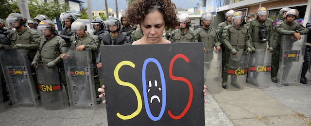 A woman protests against the government of Venezuelan President Nicolas Maduro in front of riot policemen outside the Cuban embassy in Caracas on February 25, 2014. Angry Venezuelan students geared up to stage a fresh rally on Tuesday, the latest in three weeks of anti-government protests that have left at least 14 people dead. AFP PHOTO/JUAN BARRETO (Photo credit should read JUAN BARRETO/AFP/Getty Images)